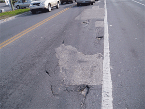 This road shows the effect of vehicle braking at an intersection. Even where there is no winter frost, potholes develop.